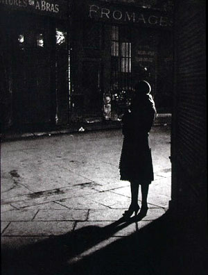 Black & white photo of prostitute on street corner by Brassai
